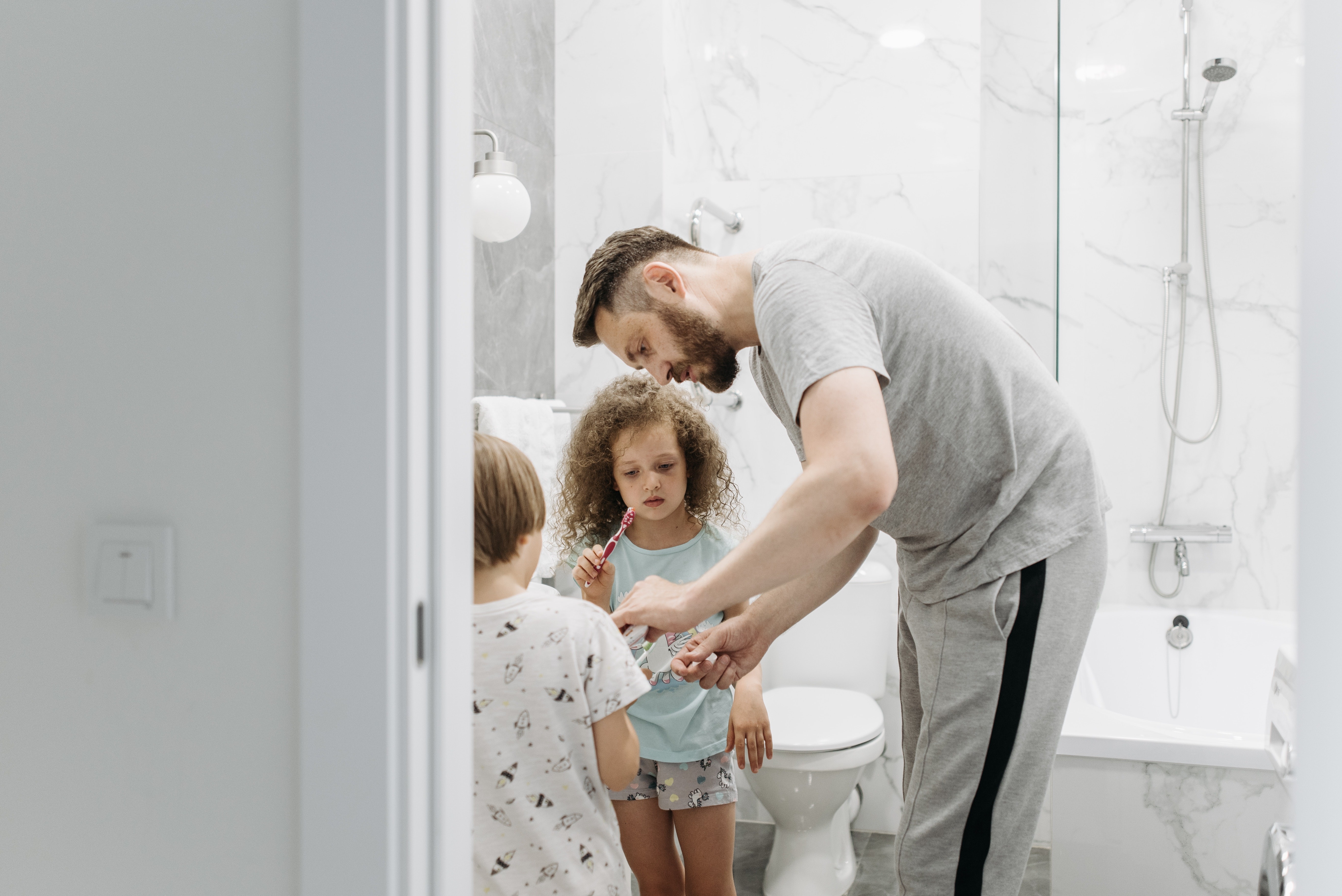 Pai ajudando os filhos a escovarem os dentes (Foto:  Pavel Danilyuk/Pexels)