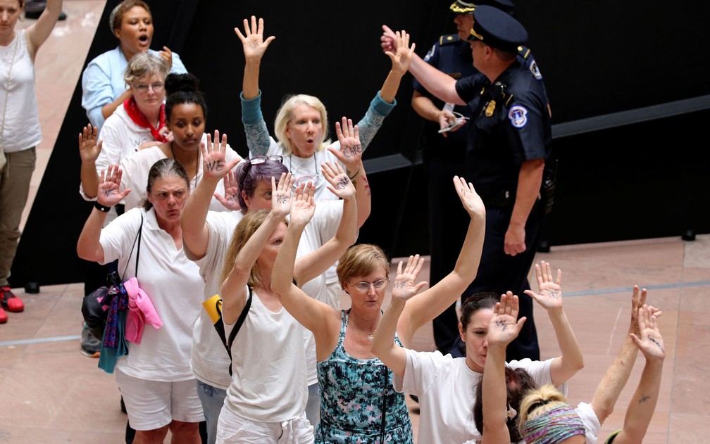 Policiais do Capitólio, em Washington, prendem manifestantes que protestavam contra a separação de famílias de imigrantes, na quinta-feira (28) (Foto: Reuters/Jonathan Ernst)