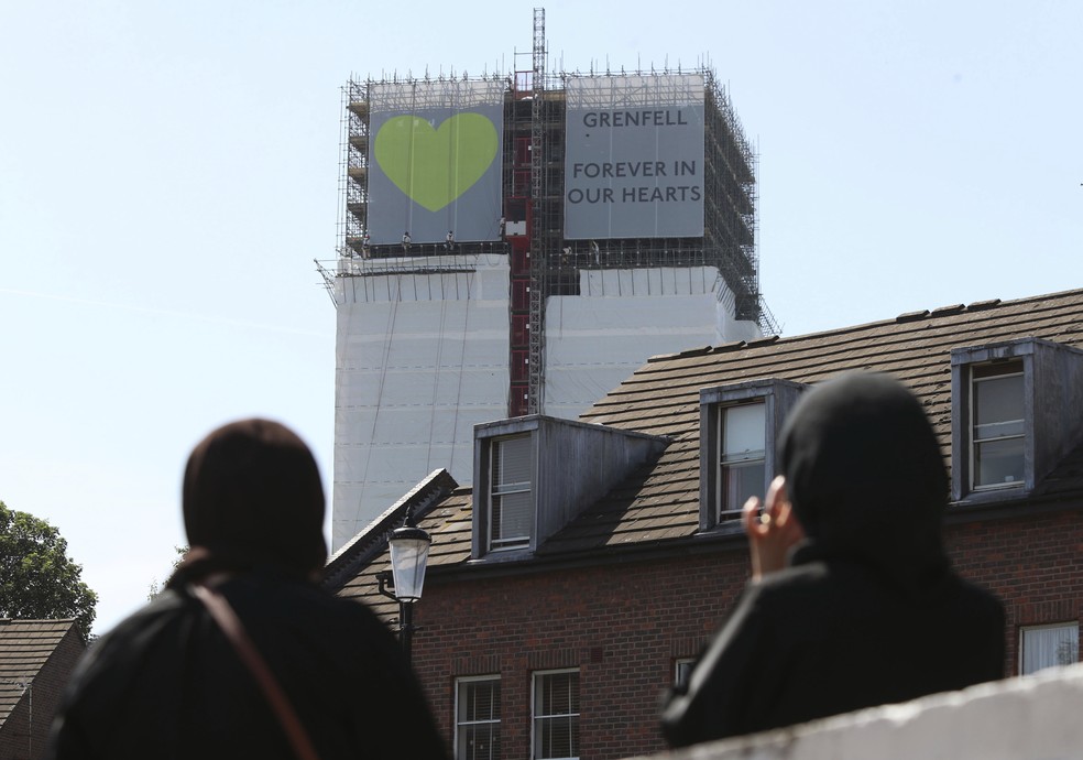 Mulheres observam faixa pendurada na Torre Grenfell, em Londres. — Foto: Yui Mok/PA via AP/Arquivo