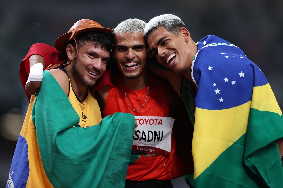 Petrucio Ferreira e Thomaz de Moraes, com bandeiras do Brasil, abraçam o marroquino — Foto: Alex Pantling/Getty Images