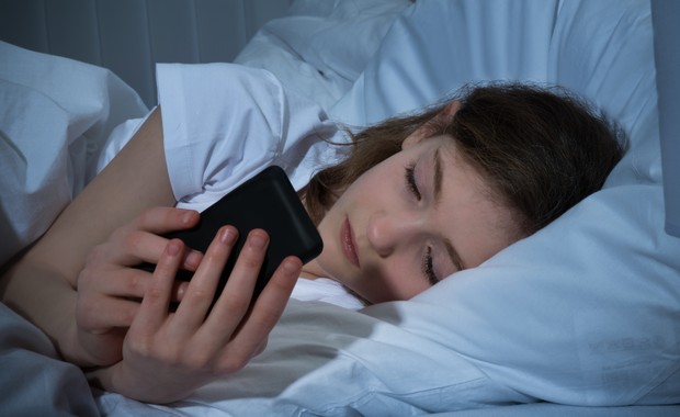 Menina mexendo no celular na cama (Foto: Thinkstock)
