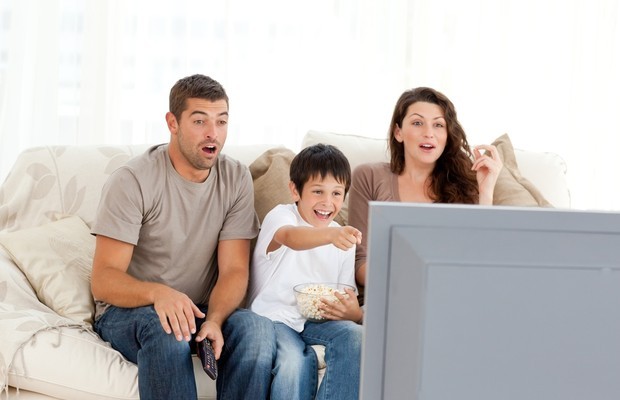 Pais assistindo televisão com os filhos (Foto: ThinkStock)