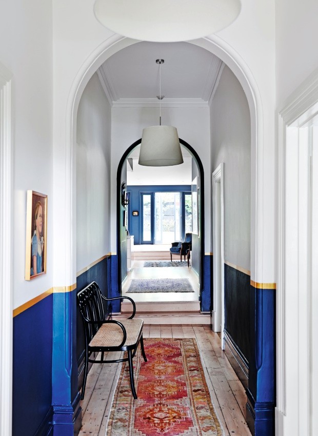 Corredor. O azul se estendeu para a passagem que liga os fundos da casa aos quartos. A parede foi pintada até a metade. Acima há uma faixa dourada, em sintonia perfeita com a cor da moldura do quadro (Foto: Lisa Cohen / Living Inside)