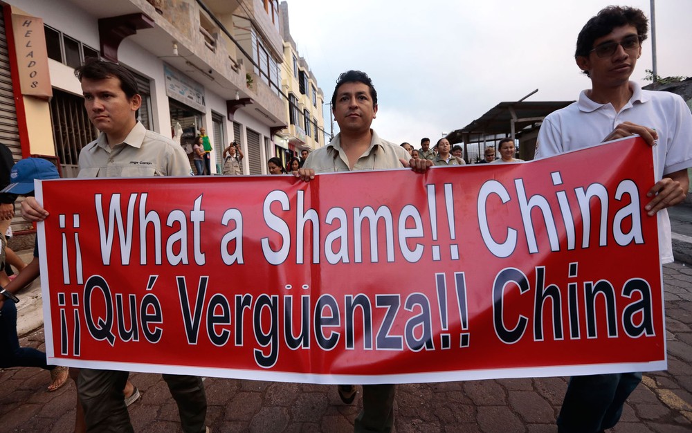 Moradores da ilha de Santa Cruz, nas Galápagos, exibem cartaz contra a China em protesto pela pesca ilegal de tubarões em 14 de agosto (Foto: Juan Cevallos/AFP)