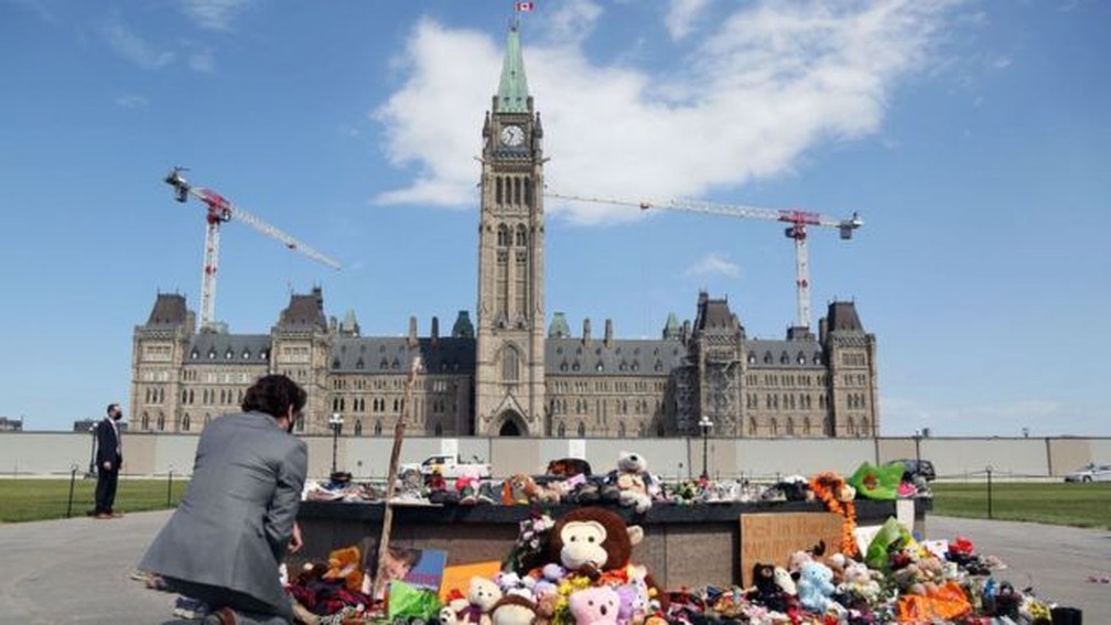Trudeau, ajoelhado diante de um dos memoriais nesta semana, se disse 'chocado' com a descoberta — Foto: Getty Images/BBC