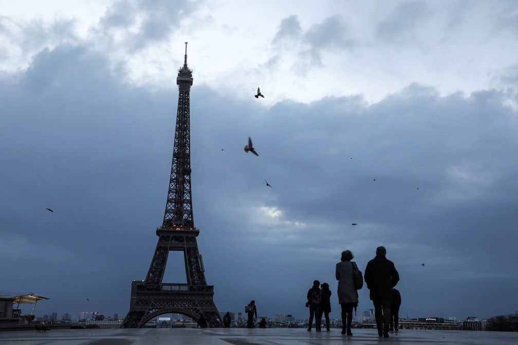 Visitantes caminham no Trocadero, na frente à Torre Eiffel, em Paris, nesta quarta-feira (3)   (Foto: Ludovic Marin / AFP)