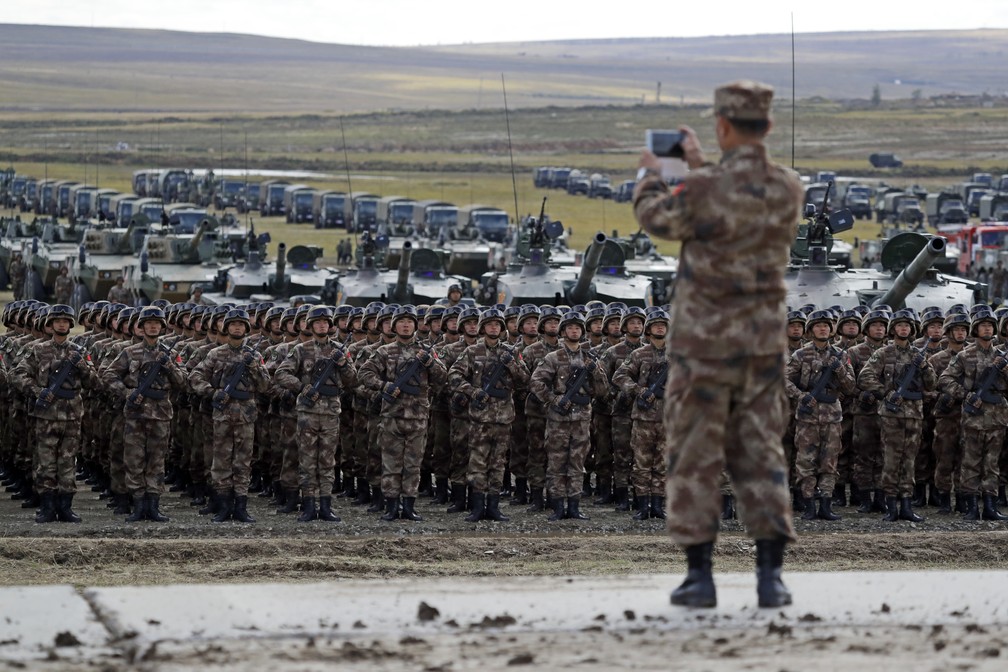 Soldado chinês tira foto de tropa e veículos nesta quinta-feira (13) durante os exercícios militares Vostok-2018, na Rússia — Foto: Sergei Grits/AP Photo