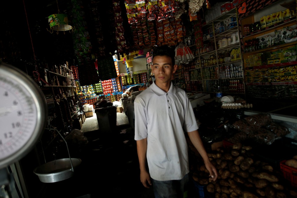 Homem cuida de loja em Tegucigalpa, Honduras, durante apagão que atingiu a América Central nesta segunda-feira (16) — Foto: Jorge Cabrera/Reuters