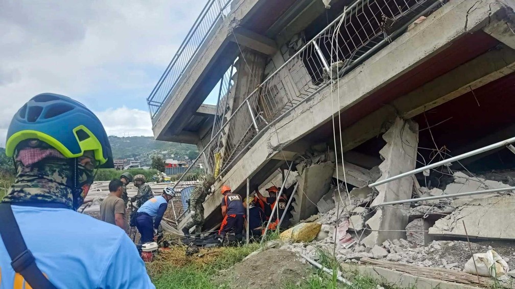 Equipes de resgate tentam retirar uma pessoa preso sob escombros de prédio desmoronado em La Trinidad, província de Benguet, norte das Filipinas, após forte terremoto sacudir o país — Foto: Bureau of Fire Protection via AP Photo