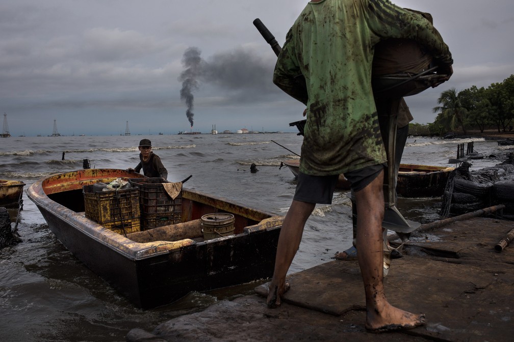 9 de julho - Pescadores cobertos de óleo preparam barco para pesca no Lago Maracaibo perto do terminal de envio de óleo cru La Salina em Cabimas, na Venezuela — Foto: Rodrigo Abd/AP