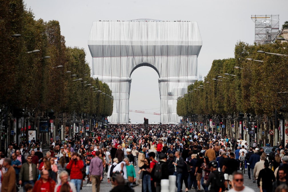 Pedestres caminham perto do Arco do Triunfo, embrulhado como parte de uma instalação de arte chamada "L'Arc de Triomphe, Wrapped", concebida pelo artista falecido Christo, na avenida Champs Elysees, no dia sem carro em Paris — Foto: Benoit Tessier/Reuters