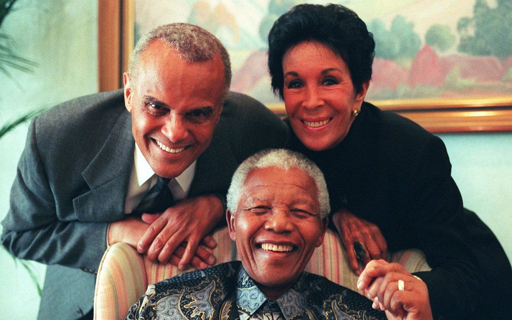 O ator e cantor americano Harry Belafonte posa com sua mulher, Julie ao lado do presidente Sul-Africano Nelson Mandela em Pretória em 1999. — Foto: Themba Hadebe/AP