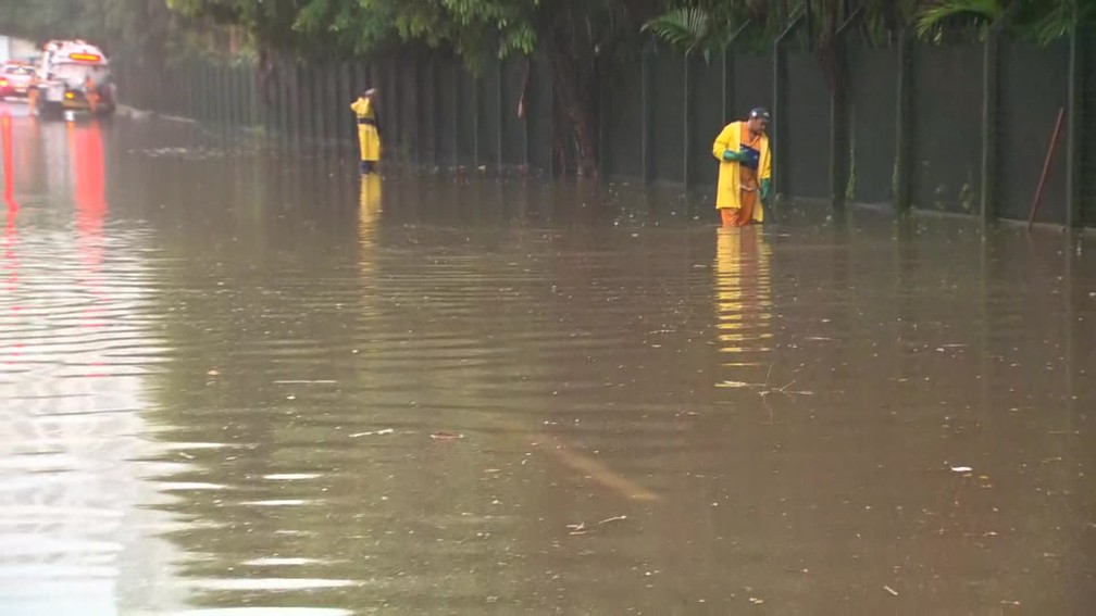 FuncionÃ¡rios da prefeitura tentam escoar a Ã¡gua na Autoestrada Lagoa-Barra â Foto: ReproduÃ§Ã£o/TV Globo
