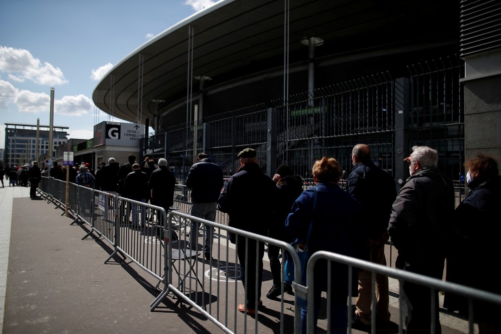 Pessoas fazem fila do lado de fora do Stade de France, em Saint-Denis, periferia de Paris, nesta terça (6). O estádio foi aberto como posto de vacinação na França — Foto: Gonzalo Fuentes/Reuters