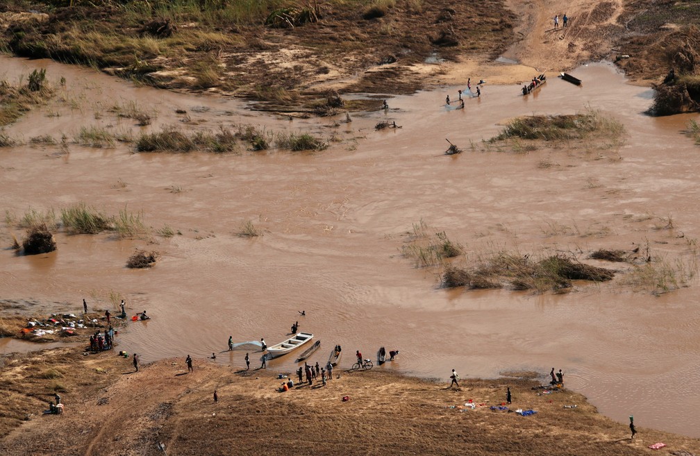 Pessoas tentam atravessar rio em Moçambique em ponto onde ponte foi arrastada pelas água, perto do vilarejo de João Segredo — Foto: Mike Hutchings/Reuters