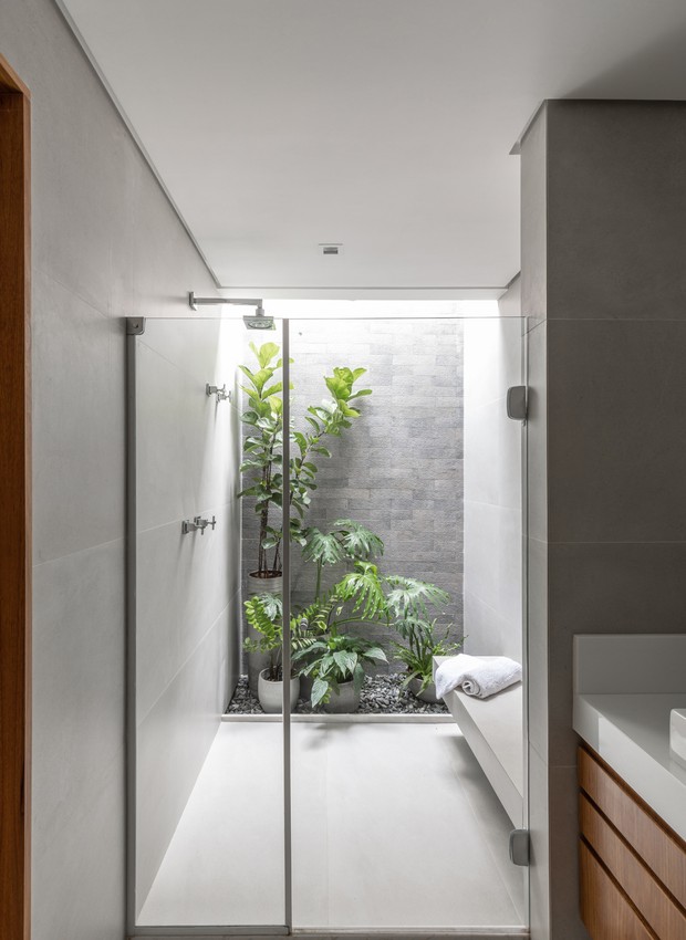 BATHROOM |  The location of the new room made it impossible to open windows, so ventilation and lighting are provided through a skylight, which allowed the creation of a small internal garden.  Neutral Portobello coating contrasts with the wood (Photo: Manuel Sá / Disclosure)