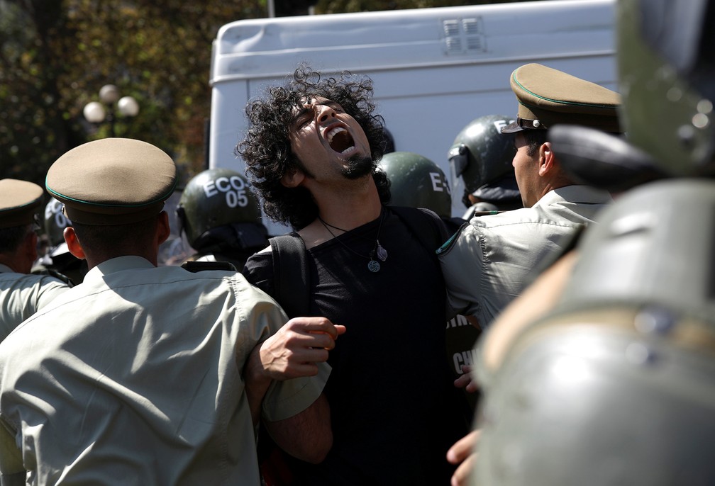 Homem é detido por policiais durante protesto contra Jair Bolsonaro neste sábado (23) diante do Palácio La Moneda, em Santiago — Foto: Pablo Sanhueza/Reuters