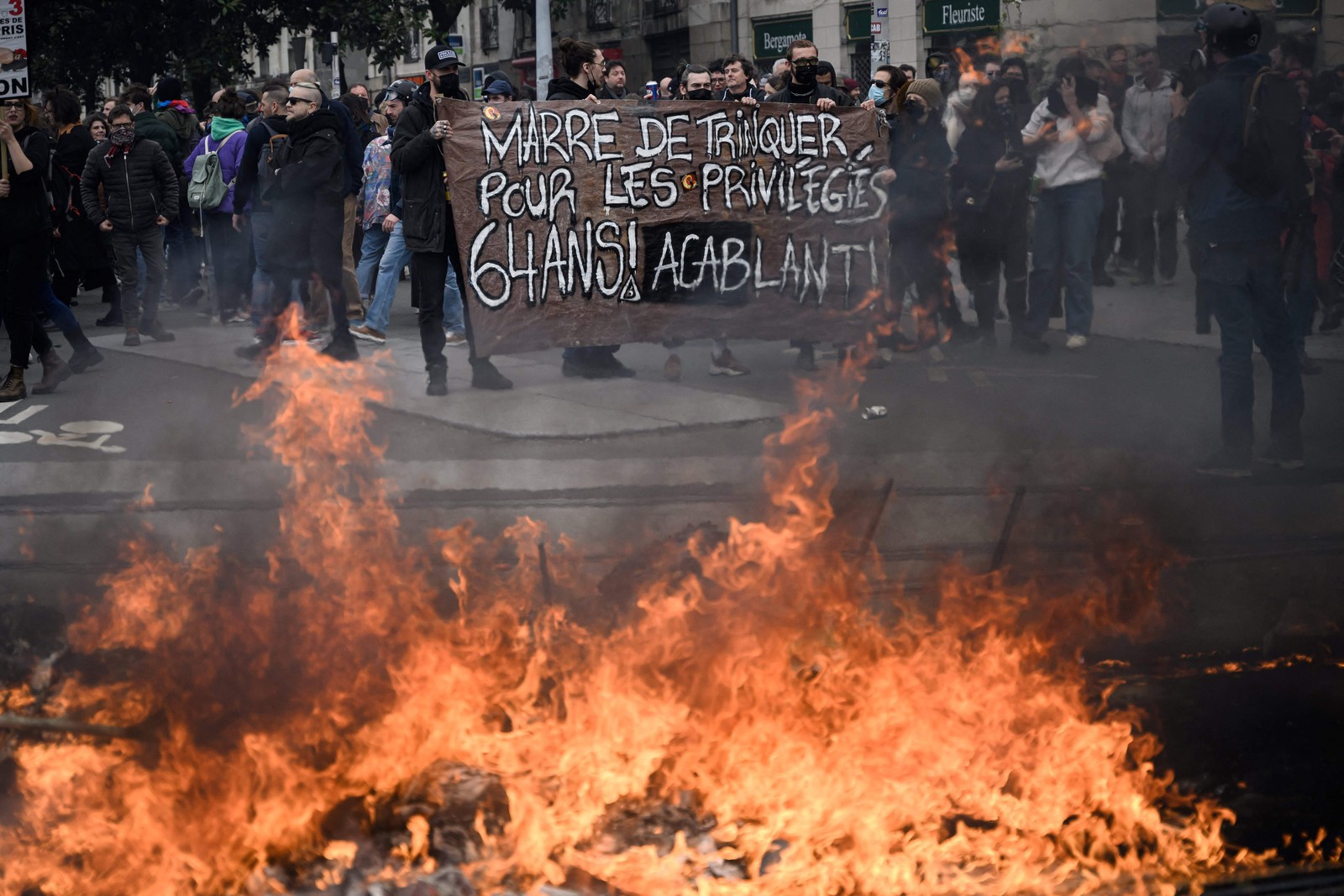 Manifestantes seguram um cartaz onde se lê "Estamos cansados de pagar por pessoas privilegiadas" — Foto: LOIC VENANCE / AFP