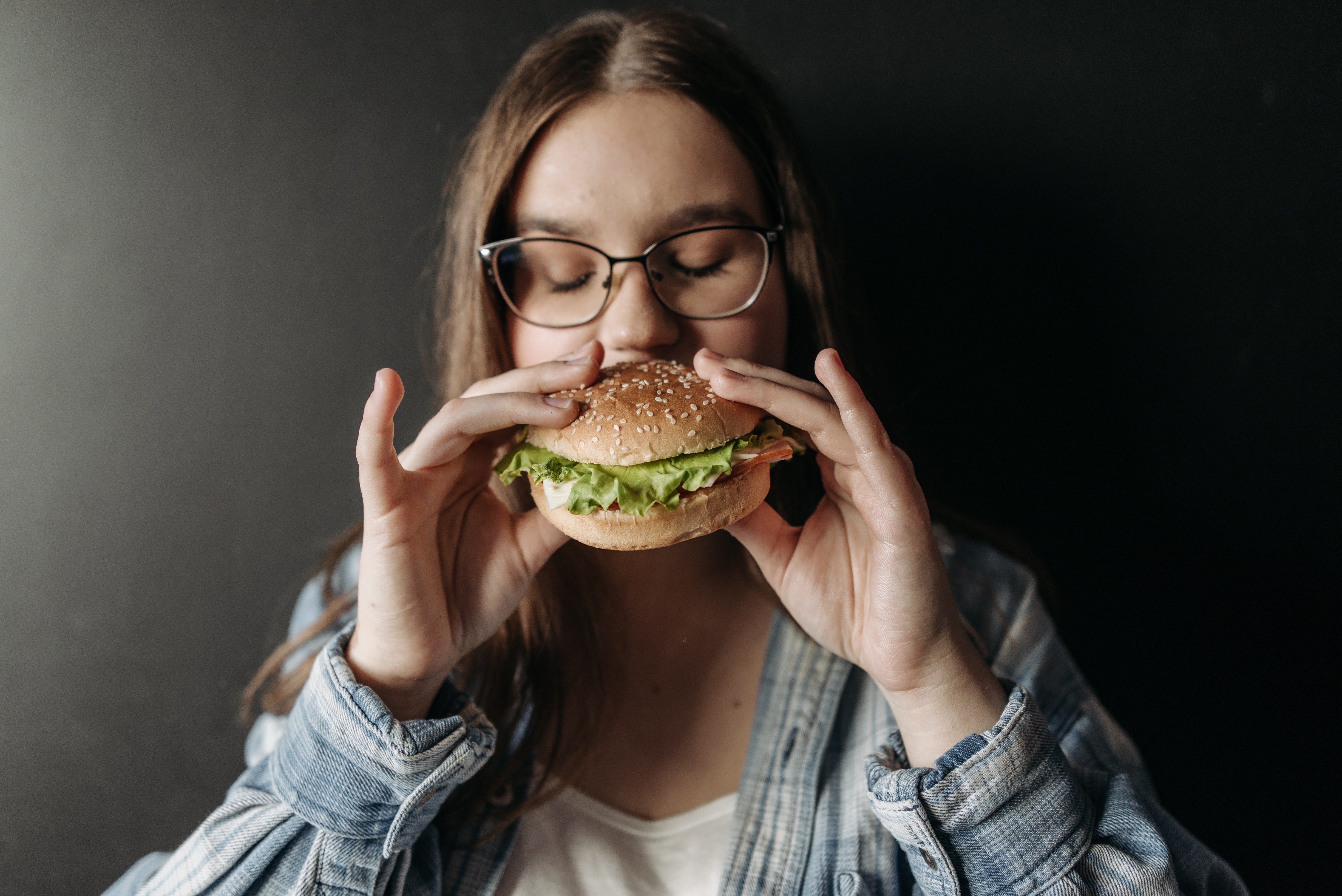 Adolescente comendo hamburguer (Foto: Pavel Danilyuk/Pexels)