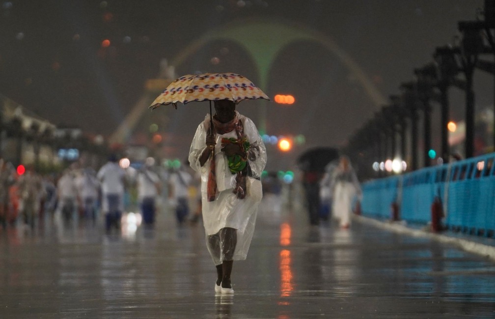 Mulher tenta se proteger da chuva na Sapucaí — Foto: Marcos Serra Lima/G1