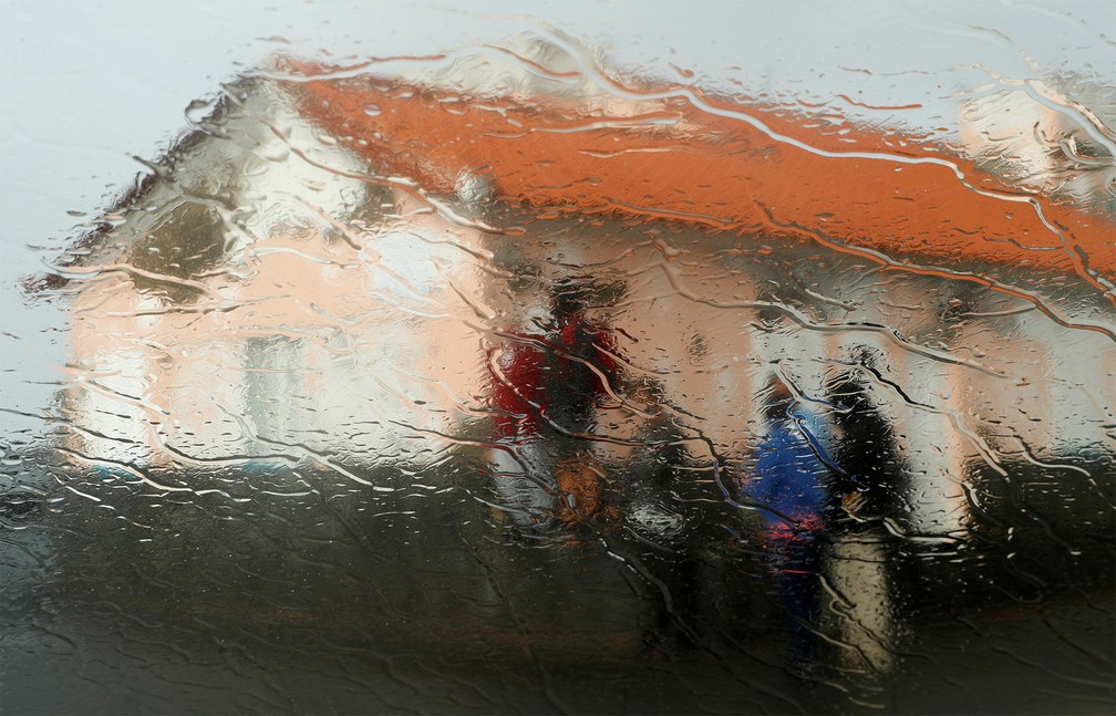 2 de outubro - Pessoas são vistas através de uma janela molhada pela chuva enquanto ondas rebentam na costa de Açores, arquipélago português no Atlântico. O local aguarda a chegada do furacão Lorenzo — Foto: Rafael Marchante/Reuters