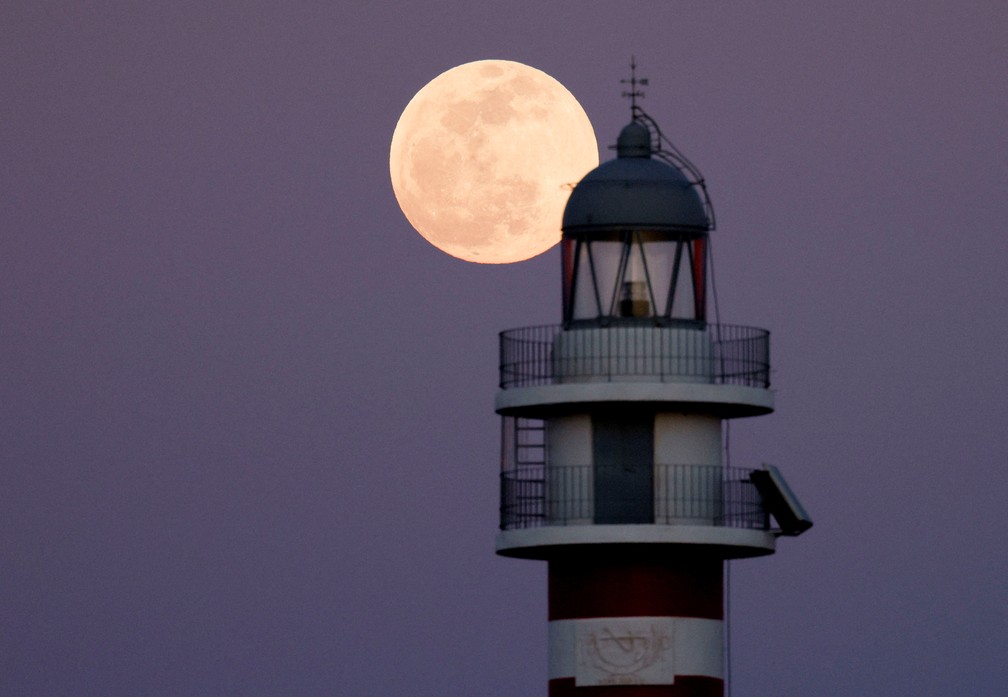 Espanha: Lua cheia nasce atrás do farol de Arinaga, nas Ilhas Canárias, neste domingo, 15 — Foto: Borja Suarez/Reuters