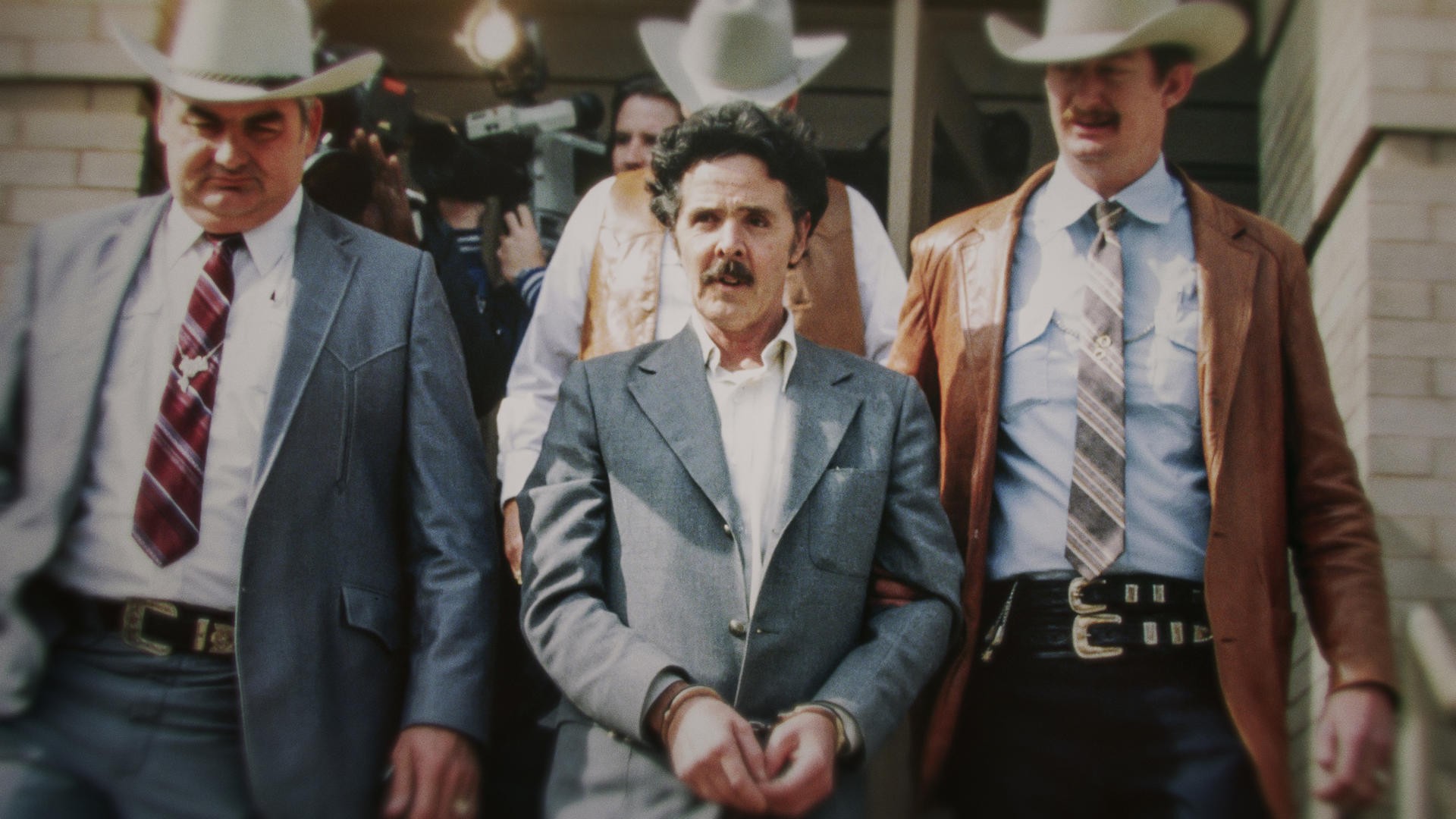 The Confession Killer — Henry Lee Lucas (center) being escorted by Ranger Bob Prince (left) and task force (Foto: Divulgação)