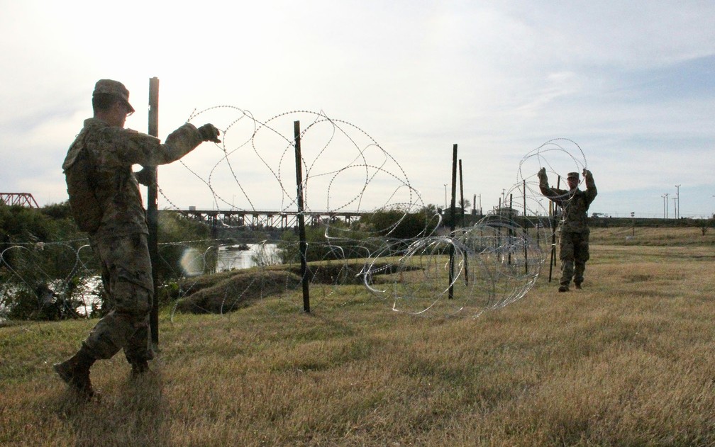 Soldados do 19º Batalhão de Engenharia de Kentucky instalam cercas de arame farpado nas margens do Rio Grande, em Laredo, no Texas, no domingo (18) — Foto: Thomas Watkins/AFP