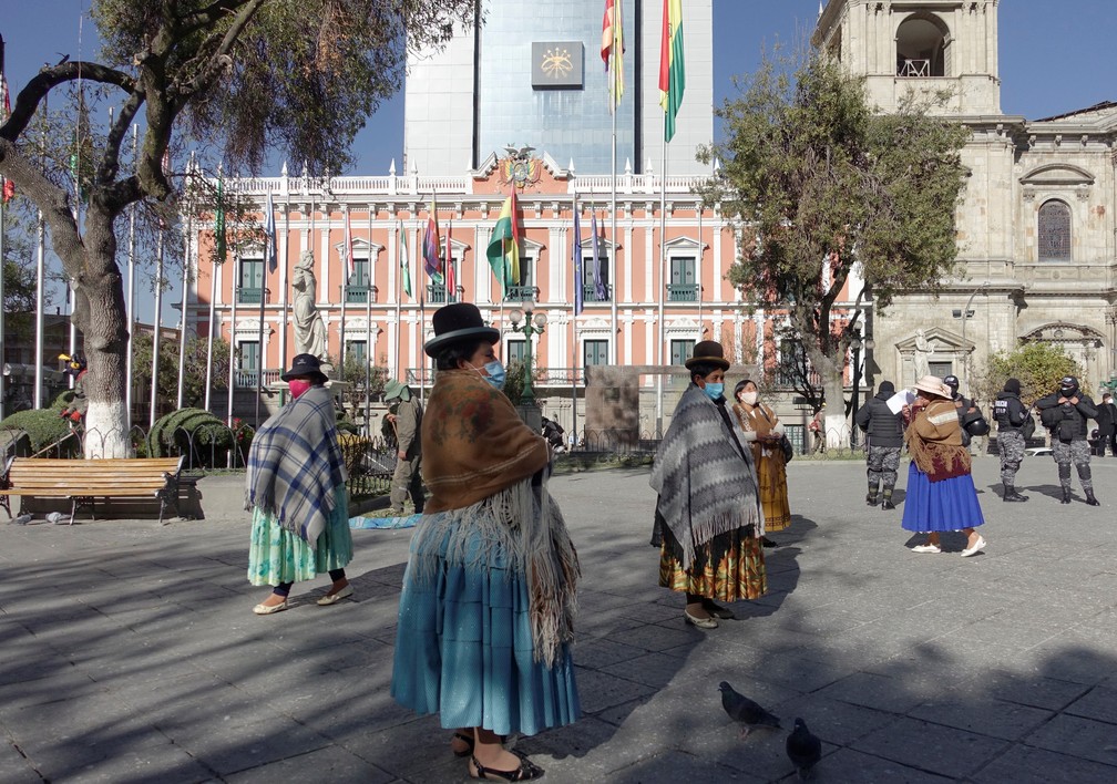 Mulheres passam, de máscaras, em frente ao Palácio Presidencial da Bolívia em La Paz, em foto de 13 de julho — Foto: David Mercado/Reuters