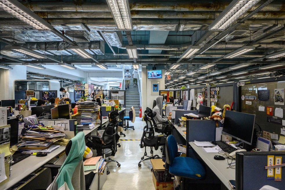 Funcionários trabalham na redação do jornal 'Apple Daily', em Hong Kong, em 17 de junho de 2021, após a polícia de Hong Kong prender o editor-chefe e mais 4 executivos do jornal pró-democracia — Foto: Anthony Wallace/AFP