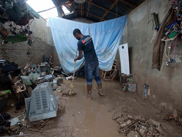 Professor limpa casa após passagem do furacão Matthew por Les Cayes, no Haiti (Foto: AP)