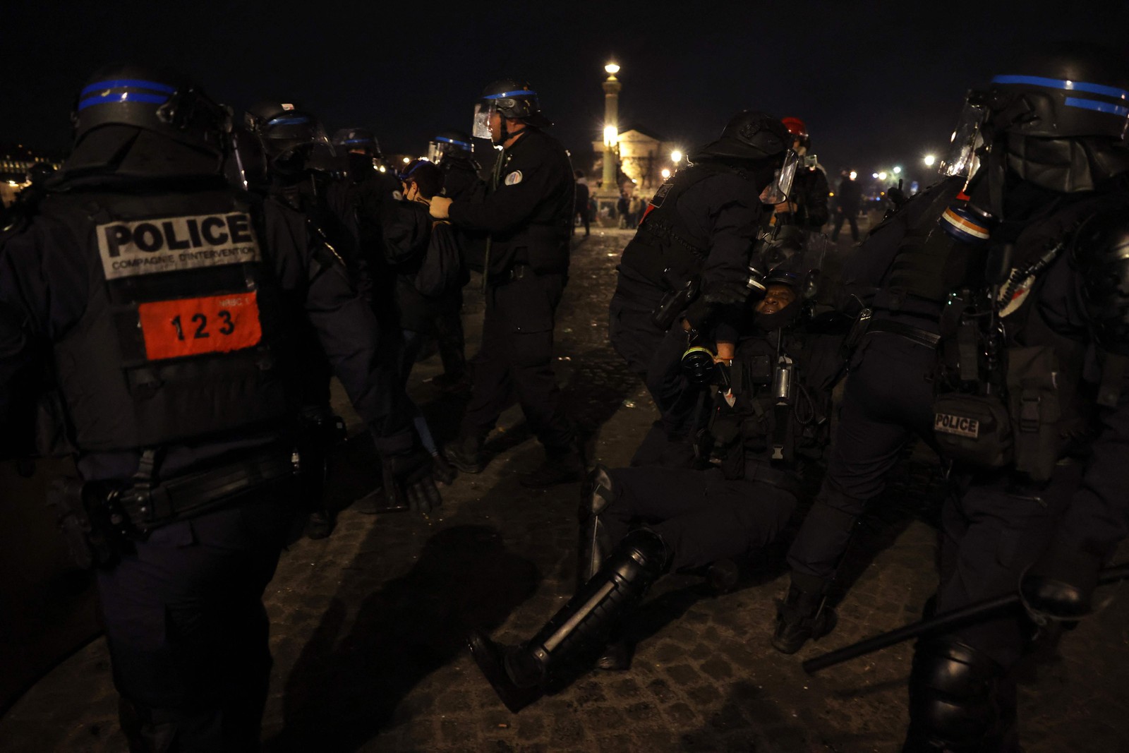Um policial francês é socorrido por colegas durante confronto com manifestantes na Praça da Concórdia, em Paris  — Foto: Thomas SAMSON / AFP