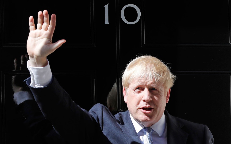 O primeiro-ministro britÃ¢nico, Boris Johnson, acena em frente ao nÃºmero 10 de Downing Street, em Londres, na quarta-feira (24) â€” Foto: AP Photo/Frank Augstein