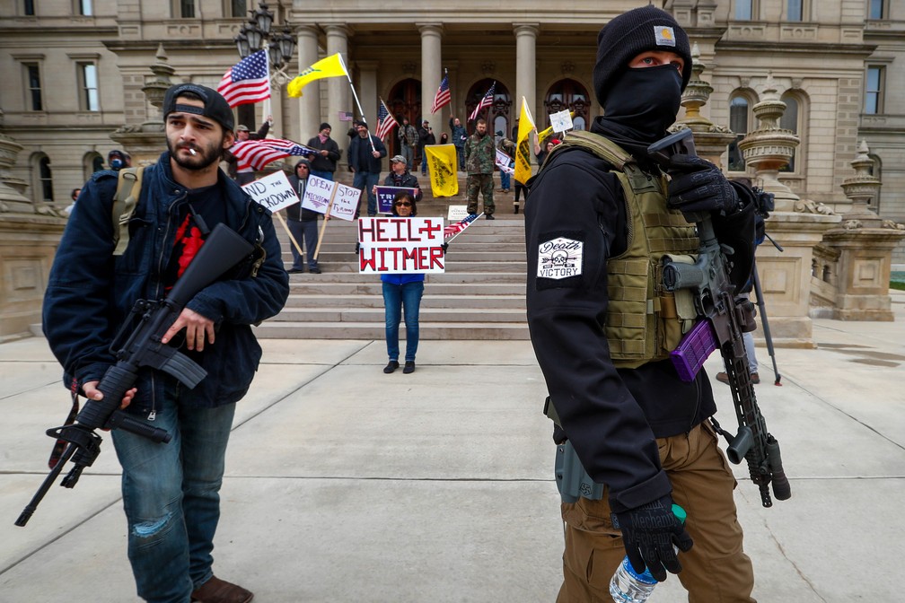 15 de abril - Homens carregam rifles perto dos degraus do edifício do Capitólio do Estado em Lansing, no Michigan, nos EUA, durante um protesto contra as ordens da governadora Gretchen Whitmer de manter as pessoas em casa e as empresas fechadas durante a pandemia de Covid-19  — Foto: Paul Sancya/AP