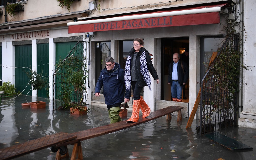  Turistas usam uma passarela improvisada para deixar hotel em Veneza — Foto: Marco Bertorello / AFP Photo 