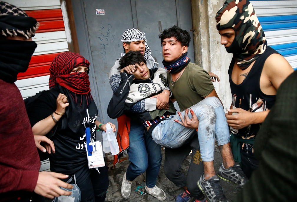 Manifestantes é carregado após ser ferido em protesto em Bagdá, no Iraque, nesta quarta-feira (27) — Foto: Thaier al-Sudani/Reuters