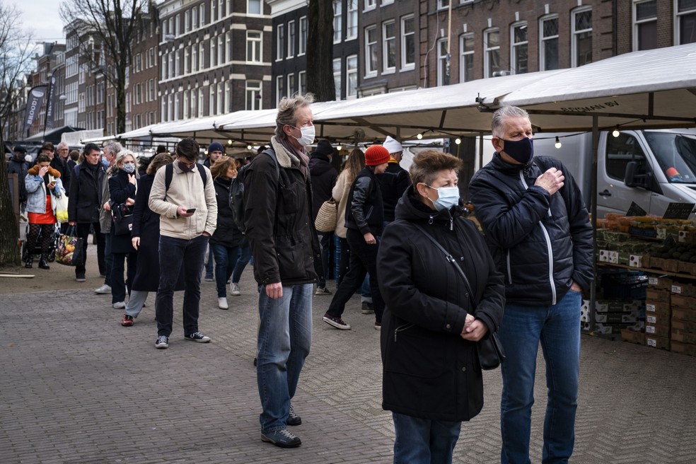 Pessoas usando máscara de proteção contra a Covid-19 formam fila para fazer compras no mercado Lindengracht, em Amsterdã, em dezembro de 2020 — Foto: Ramon van Flymen/ANP via AFP
