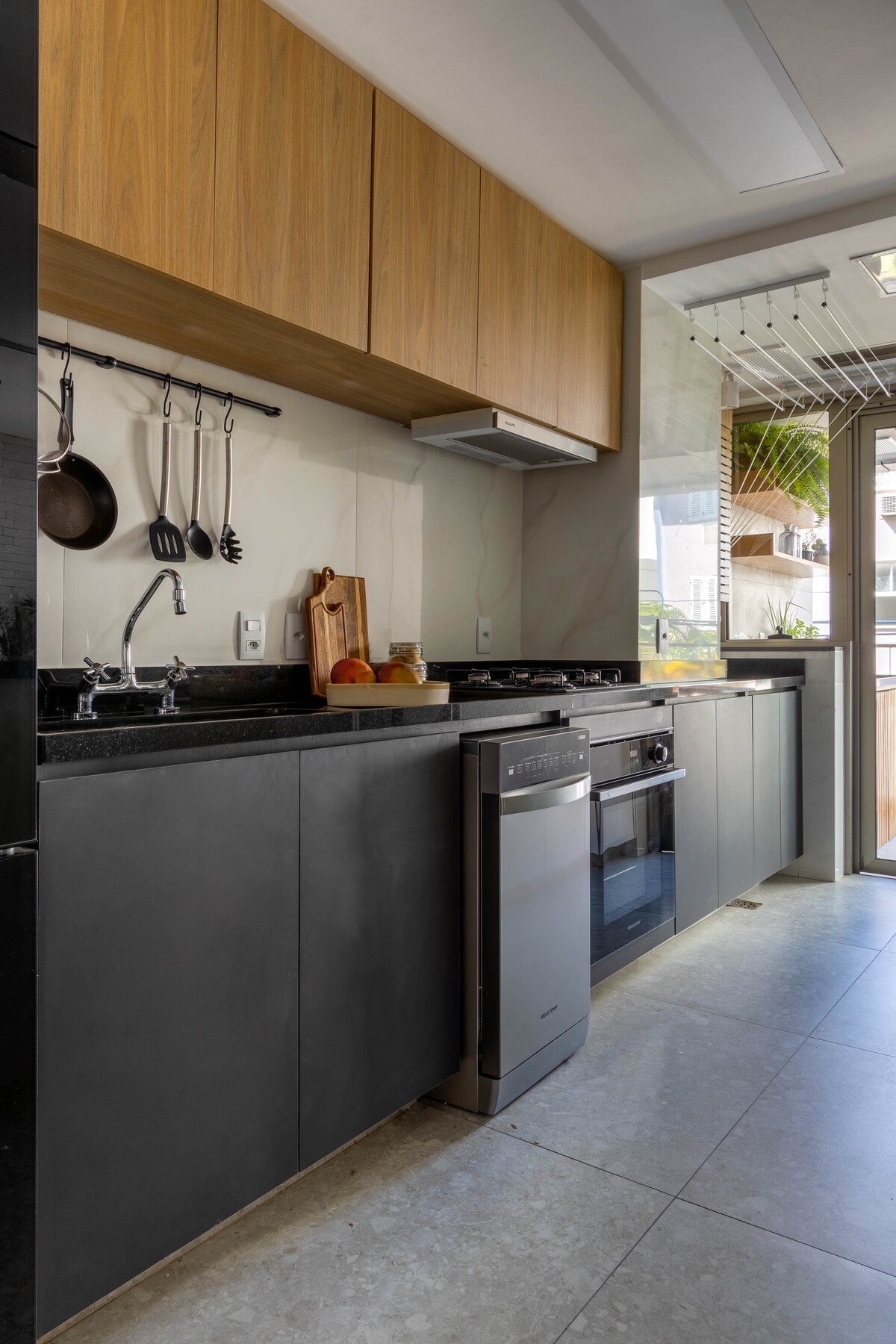 COZINHA | A cozinha tem abertura para a varanda e para a sala de estar. Um painel de freijó permite fechar a cozinha para dar privacidade (Foto: André Nazareth / Divulgação)