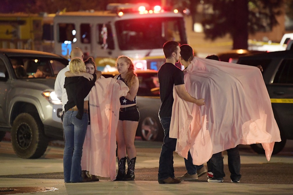 Jovens se abraÃ§am perto de bar da CalifÃ³rnia em que atirador abriu fogo na madrugada desta quinta-feira (8) e matou mais de 10 pessoas â€” Foto: Mark J. Terrill/AP Photo