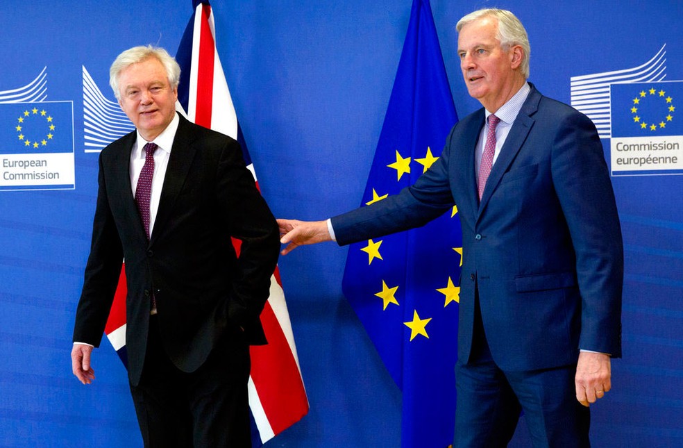Negociador europeu para o Brexit, Michel Barnier, (à direita) toca o braço de David Davis, negociador britânico do Brexit, após encontro em Bruxelas, nesta segunda-feira (19)  (Foto: Virginia Mayo/AP)