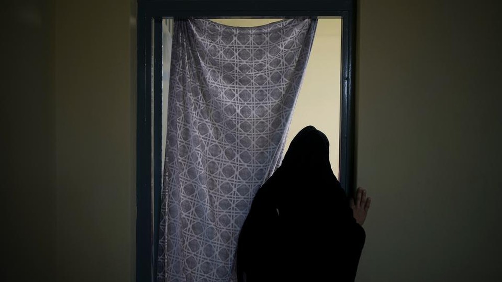 Mulher afegã de costas em frente a porta em 23 de setembro de 2021 — Foto: Felipe Dana/AP
