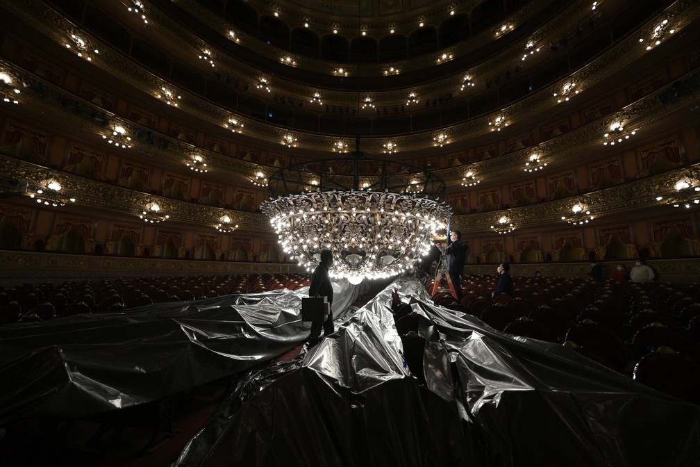 Funcionários do Teatro Colón de Buenos Aires fazem manutenção em lustre majestoso antes da reabertura da casa — Foto: JUAN MABROMATA / AFP
