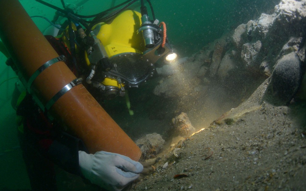 Foto não datada e divulgada na sexta (18) mostra mergulhador recolhendo pedaços de ossos nos destroços do navio Rooswijk, no leito da costa de Ramsgate, na Inglaterra (Foto: HO/Historic England/AFP)