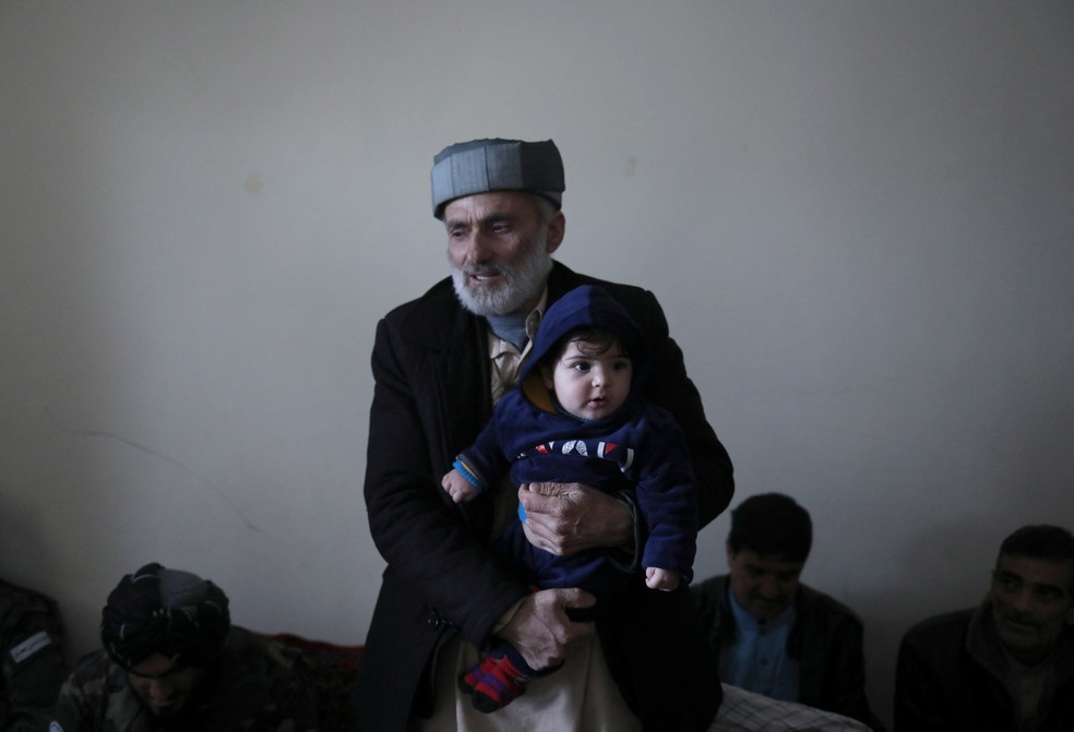 Mohammad Qasem Razawi segura seu neto Sohail Ahmadi na casa de Hamid Safi em Cabul — Foto: Ali Khara/Reuters