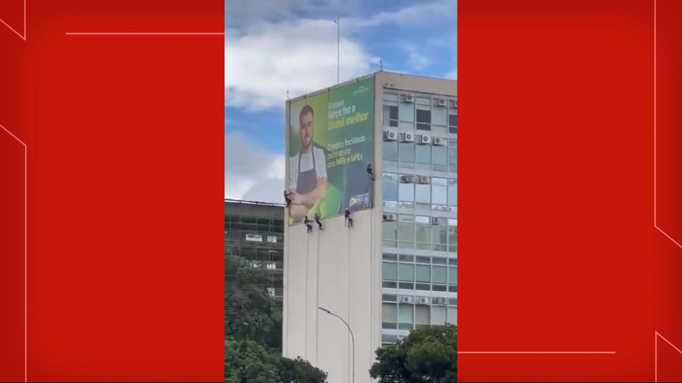 Operários colocam propaganda de governo em fachada de ministério, em Brasília — Foto: Reprodução