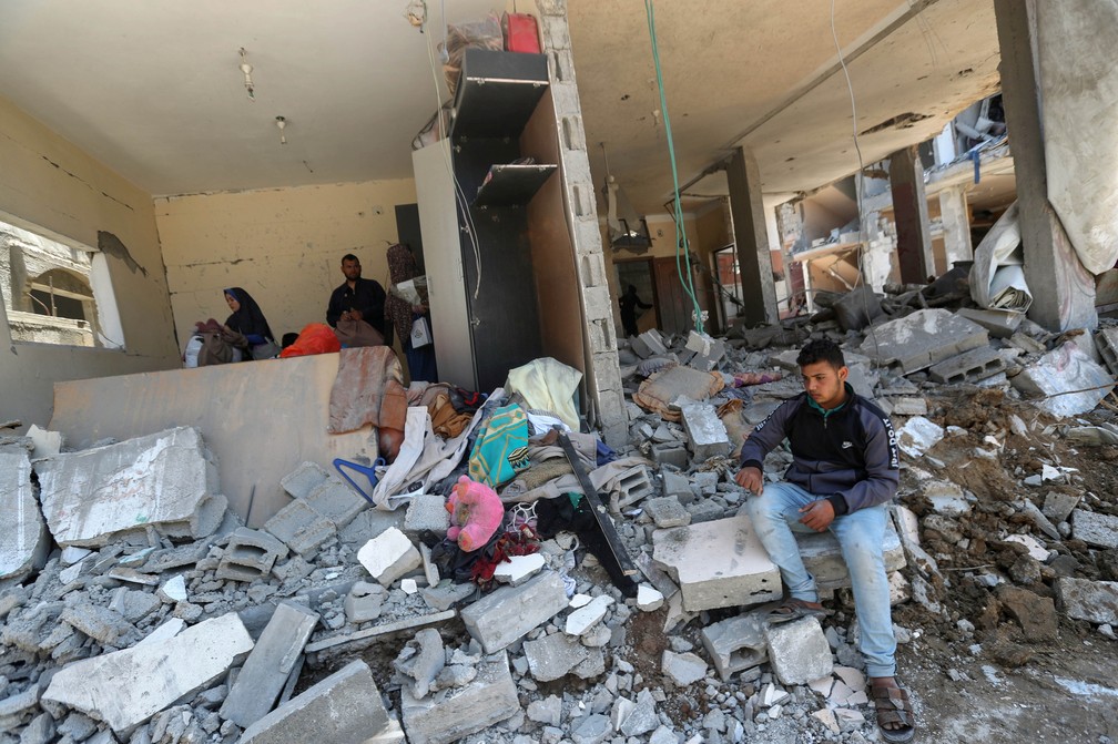 Palestino em destroços de casa atingida por bombardeios na Faixa de Gaza, em 14 de maio de 2021 — Foto: Mohammed Salem/Reuters
