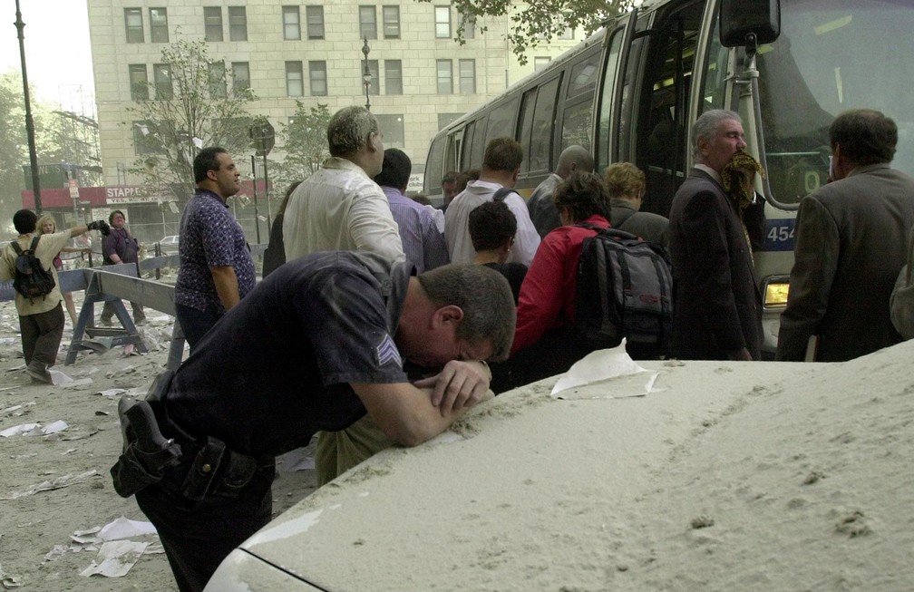 Exausto, um policial apoia a cabeça na traseira de um carro para descansar após a queda das torres do World Trade Center em 11 de setembro de 2001 — Foto: Stan Honda/AFP/Arquivo