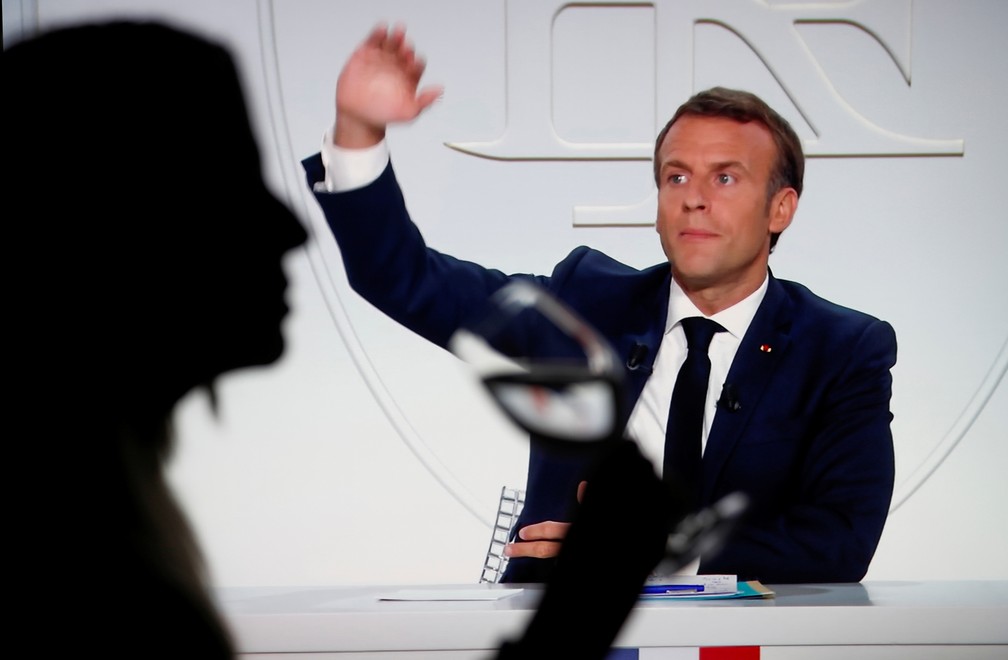 Mulher acompanha entrevista pela televisão com Emmanuel Macron, presidente da França, nesta quarta (14) — Foto: Eric Gaillard/Reuters