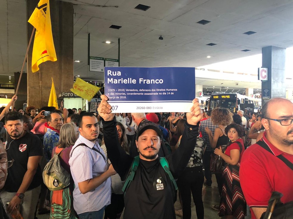 Manifestante segura placa com nome da rua Marielle Franco em ato na rodoviária do Plano Piloto, em Brasília — Foto: Nicole Angel/ G1