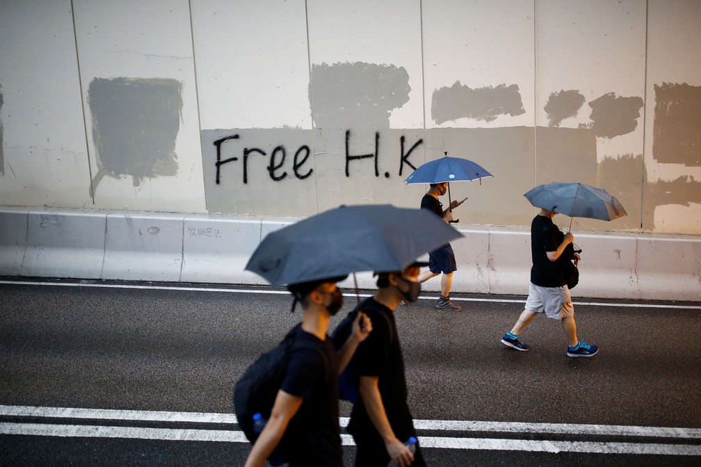 Manifestantes passam em frente a muro com a mensagem â??Hong Kong Livreâ?? neste domingo (18)  â?? Foto: Thomas Peter/ Reuters